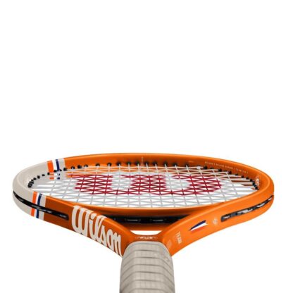 View from grip of orange, grey and blue tennis racquet from Wilson. White strings with red Wilson logo. Grey grip.