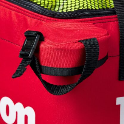 Closeup of square bag for tennis balls from Wilson in red. Black mesh on the top with white Wilson logo. Wilson in white writing on the sides of the bag.