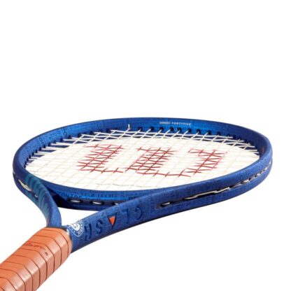 Side throat view of blue tennis racquet with clay grip and white strings with red "W" for Wilson. White Roland Garros logo at the bottom of the throat. Wilson Clash 100 v2.0 Roland Garros Edition. Clash in blue writing on the side of the beam.