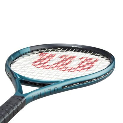 Side throat view of beam of blue matte tennis racquet with black top, white strings with red logo and black grip. Wilson Ultra 25 v4.0. Ultra in black writing on the side.