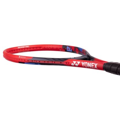 Lying view of red, black and blue tennis racquet from Yonex. Black grip. Yonex in silver writing on the side with silver Yonex logo. Yonex Vcore 100 2023 model.