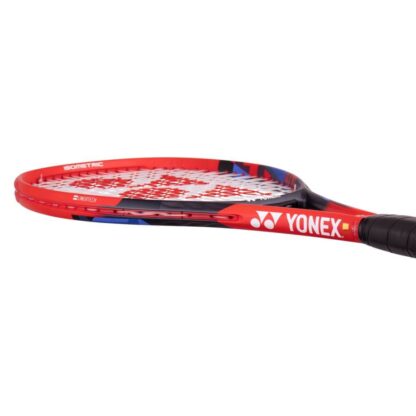 Lying view of red, black and blue tennis racquet from Yonex. White strings with red Yonex logo and black grip. Yonex in silver writing on the side with silver Yonex logo. Yonex Vcore 26 2023 model.
