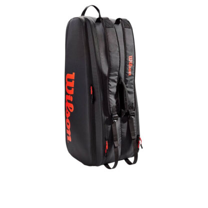 Black tennis bag with red/orange details. Wilson in red/orange writing on the side and on the shoulder strap.